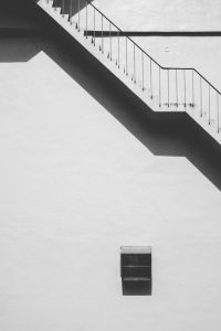 Black and white photo of a modern building's exterior staircase with strong shadows.