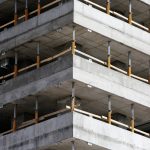 Close-up of an unfinished multi-level concrete building with steel reinforcements.