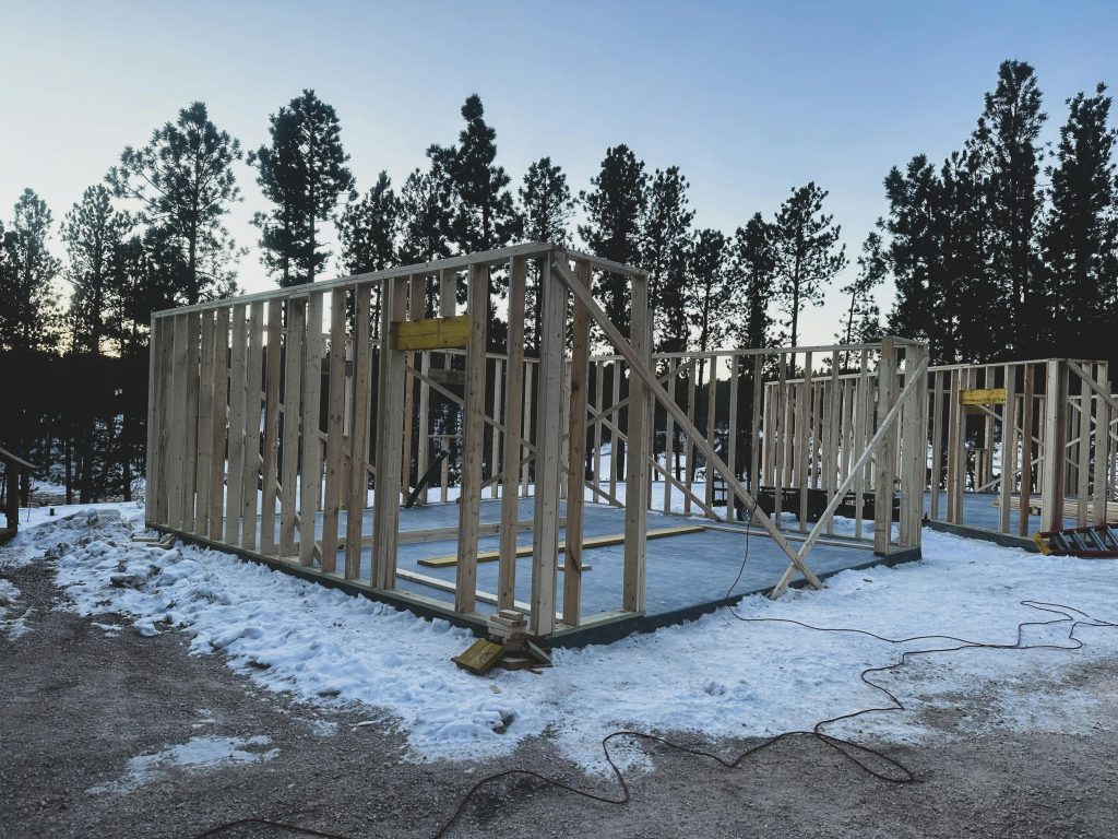 pexels-photo-23322383-23322383 Wooden frames of a house under construction on a snowy winter morning in Custer, SD.